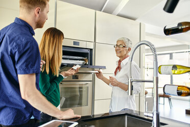 Shop assistant explaining oven to couple shopping for a new kitchen in showroom - ZEDF02448
