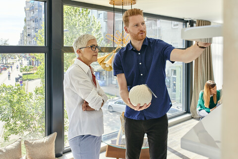 Mann und reife Frau unterhalten sich in einem Möbelgeschäft, lizenzfreies Stockfoto