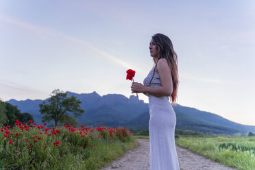 Elegant young woman holding a poppy in the countryside, Garrotxa, Spain - AFVF03247