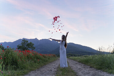 Elegant young woman throwing poppy petals in the countryside, Garrotxa, Spain - AFVF03251