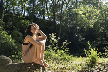 Porträt einer jungen Frau, die auf einem Felsen im Wald sitzt, Garrotxa, Spanien - AFVF03265
