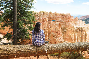 Reisende Frau sitzt auf dem Stamm eines umgestürzten Baumes und genießt die Aussicht im Bryce Canyon, Utah, USA - GEMF02977