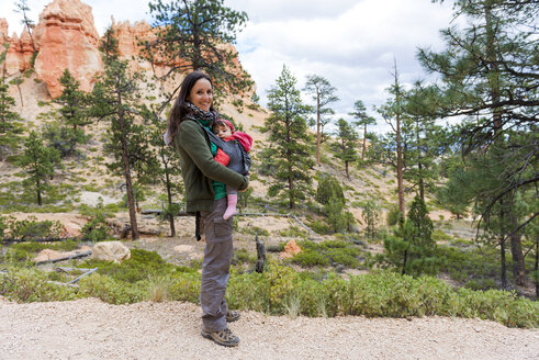 Frau trägt ihre Tochter in einer Babytrage bei den Hoodoos im Bryce Canyon, Utah, USA - GEMF02980