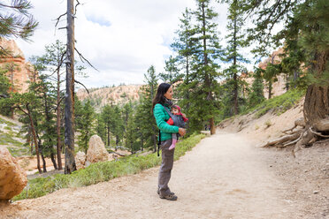 Frau trägt ihre Tochter in einer Babytrage bei den Hoodoos im Bryce Canyon, Utah, USA - GEMF02981