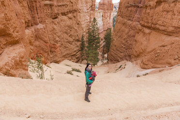 Frau trägt ihre Tochter in einer Babytrage bei den Hoodoos im Bryce Canyon, Utah, USA - GEMF02983