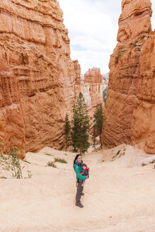 Frau trägt ihre Tochter in einer Babytrage bei den Hoodoos im Bryce Canyon, Utah, USA - GEMF02984