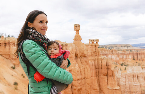 Frau trägt ihre Tochter in einer Babytrage bei den Hoodoos im Bryce Canyon, Utah, USA, lizenzfreies Stockfoto