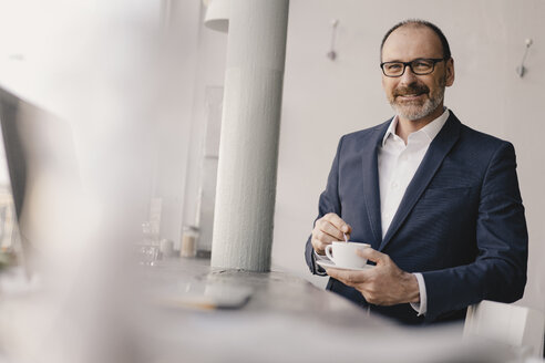 Porträt eines reifen Geschäftsmannes mit Kaffeetasse in einem Cafe - KNSF05897