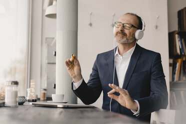 Mature businessman with closed eyes listening to music with headphones - KNSF05903