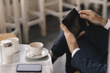 Close-up of businessman using tablet in a cafe - KNSF05913