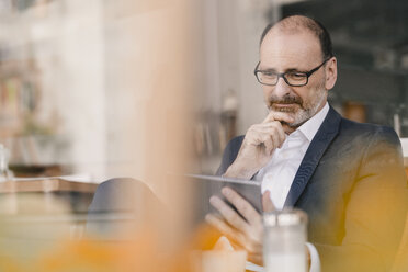 Mature businessman using tablet in a cafe - KNSF05914