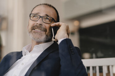 Portrait of mature businessman on cell phone in a cafe - KNSF05918