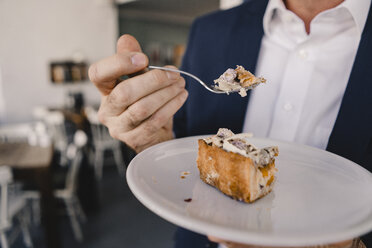 Nahaufnahme eines Geschäftsmannes, der ein Stück Kuchen in einem Café isst - KNSF05947