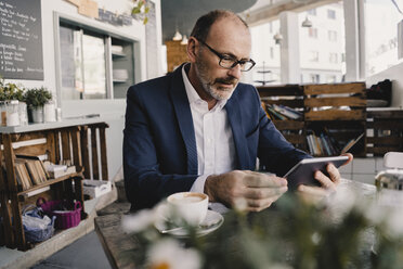 Älterer Geschäftsmann benutzt Tablet in einem Cafe - KNSF05951