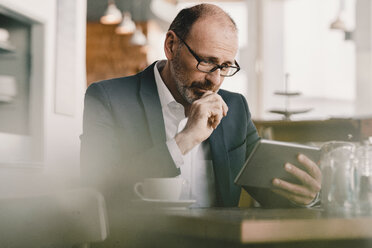 Mature businessman using tablet in a cafe - KNSF05952