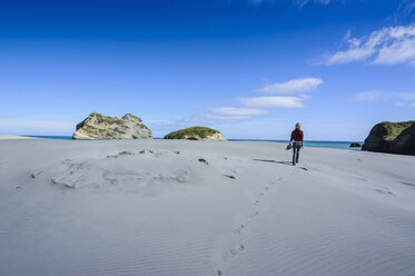 Frau beim Spaziergang in den weißen Sanddünen am Wharariki Beach, Südinsel, Neuseeland - RUNF02431