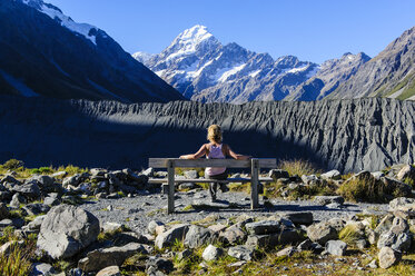 Woman stiitng on a bench and enjoying the view of Mount Cook, South Island, New Zealand - RUNF02459