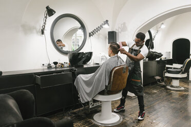 Barber cutting hair of a customer in barber shop - AHSF00493