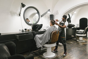 Friseur, der einem Kunden im Friseursalon die Haare schneidet - AHSF00493