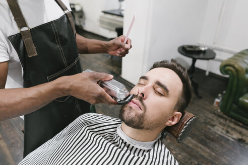 Barbier schneidet Bart eines Kunden im Friseursalon - AHSF00495