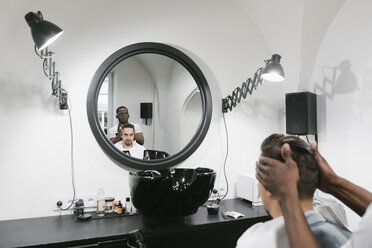 Barbier frisiert einen Kunden im Friseursalon - AHSF00498