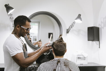 Ein lächelnder Friseur rasiert und trimmt die Haare eines Kunden in einem Friseursalon - AHSF00506