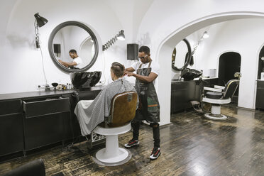 Barber cutting hair of a customer in barber shop - AHSF00507