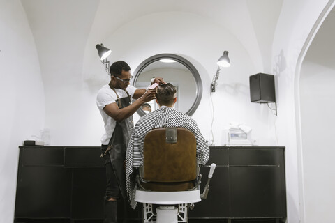 Friseur, der einem Kunden im Friseursalon die Haare schneidet, lizenzfreies Stockfoto