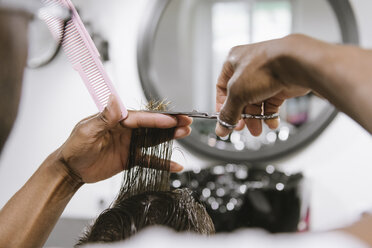 Nahaufnahme eines Friseurs, der einem Kunden im Friseursalon die Haare schneidet - AHSF00509