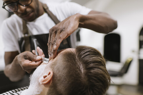 Mann, der seinen Bart mit einem Rasiermesser im Friseursalon rasiert bekommt - AHSF00514