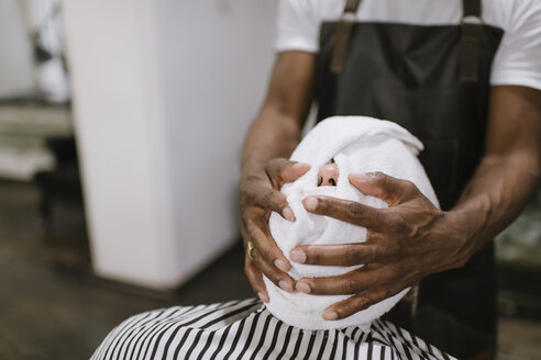 Friseur wischt das Gesicht eines Kunden mit einem heißen Handtuch ab - AHSF00515