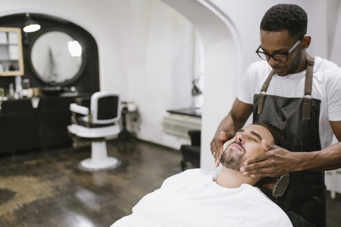Friseur, der den Bart eines Kunden nach der Rasur rasiert, in einem Friseursalon - AHSF00516