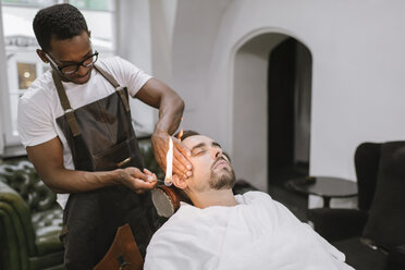 Friseur entfernt Ohrhaare eines Kunden mit Feuer im Friseursalon - AHSF00517