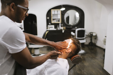 Friseur entfernt Ohrhaare eines Kunden mit Feuer im Friseursalon - AHSF00518