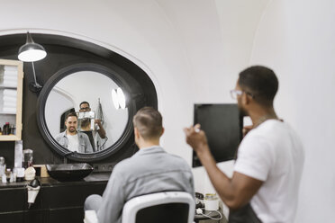 Friseur zeigt Mann seinen Haarschnitt im Spiegel im Friseursalon - AHSF00521