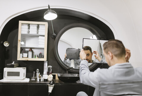 Kunde prüft seinen Haarschnitt im Spiegel eines Friseursalons, lizenzfreies Stockfoto