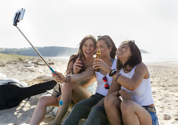 Glückliche Freundinnen mit Bierflaschen machen ein Selfie am Strand - MGOF04074