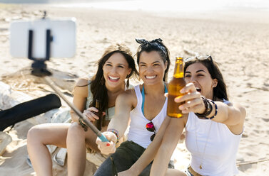 Glückliche Freundinnen mit Bierflaschen machen ein Selfie am Strand - MGOF04075