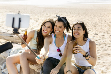 Glückliche Freundinnen mit Bierflaschen machen ein Selfie am Strand - MGOF04076