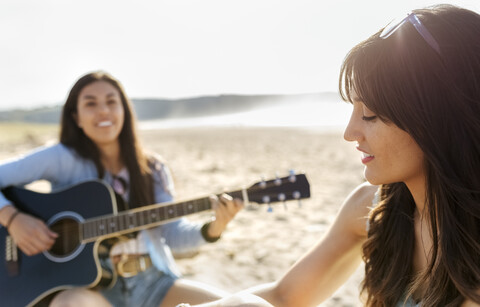 Zwei Frauen mit Gitarre am Strand, lizenzfreies Stockfoto
