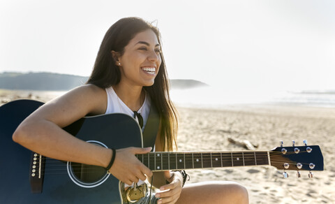 Glückliche junge Frau mit Gitarre am Strand, lizenzfreies Stockfoto