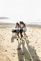 Three women with dog walking on the beach - MGOF04108