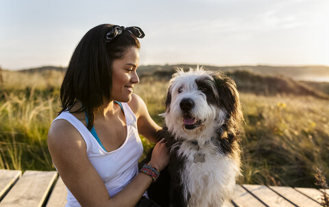 Lächelnde Frau mit Hund auf der Strandpromenade in den Dünen, lizenzfreies Stockfoto