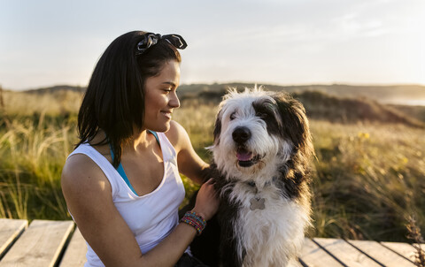 Smiling woman with dog on boardwalk in dunes stock photo