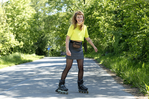 Porträt einer lachenden jungen Frau mit Inline-Skates, lizenzfreies Stockfoto