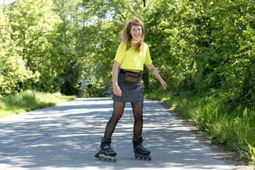 Portrait of laughing young woman with inline skates - FLLF00235