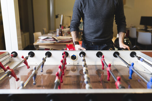 Nahaufnahme eines Mannes, der im Büro Tischfußball spielt - FMOF00682