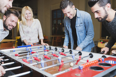 Happy colleagues playing foosball in office - FMOF00685