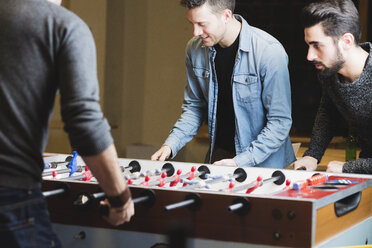 Colleagues playing foosball in office - FMOF00687