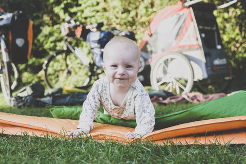 Porträt eines glücklichen Babys mit Isomatte im Gras, lizenzfreies Stockfoto